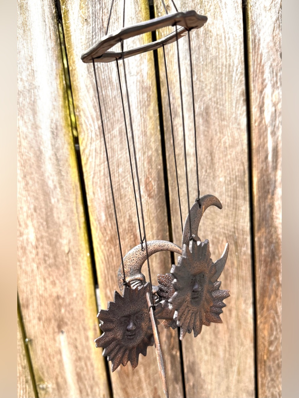 A rustic metal celestial wind chime featuring decorative sun and crescent moon